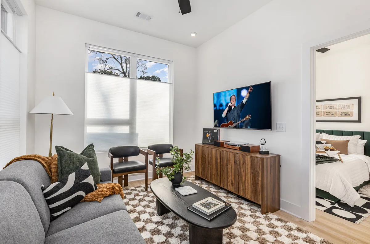 A cozy living room scene with a plush sofa, coffee table, television, and a potted plant. The atmosphere is relaxed and inviting, suggesting a comfortable environment ideal for both guests and their pets.