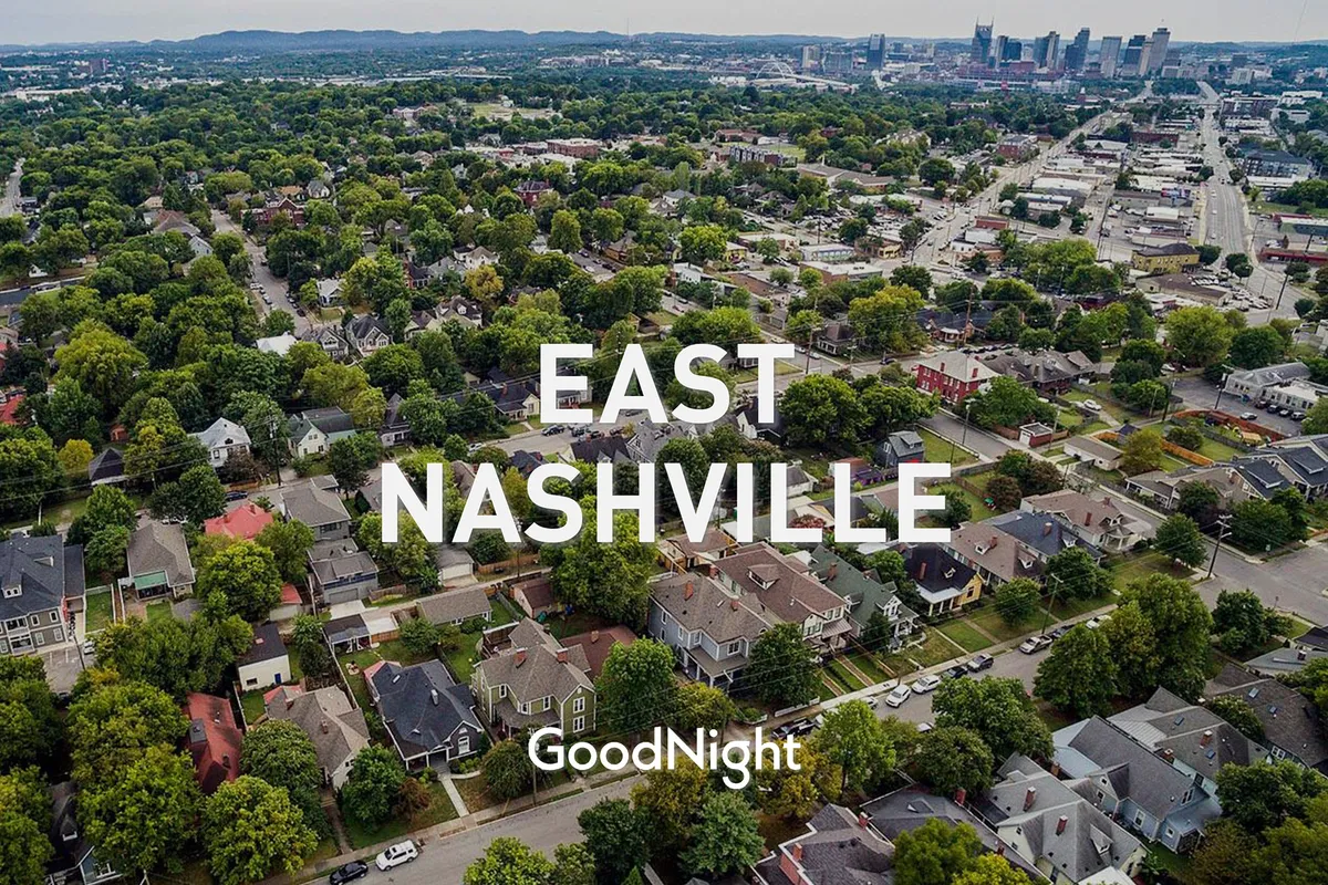A wide-angle neighborhood view showing residential homes, tree-lined streets, and Nashville’s downtown skyline in the distance. The scene is lively yet welcoming, suggesting easy access to both local art scenes and city attractions.
