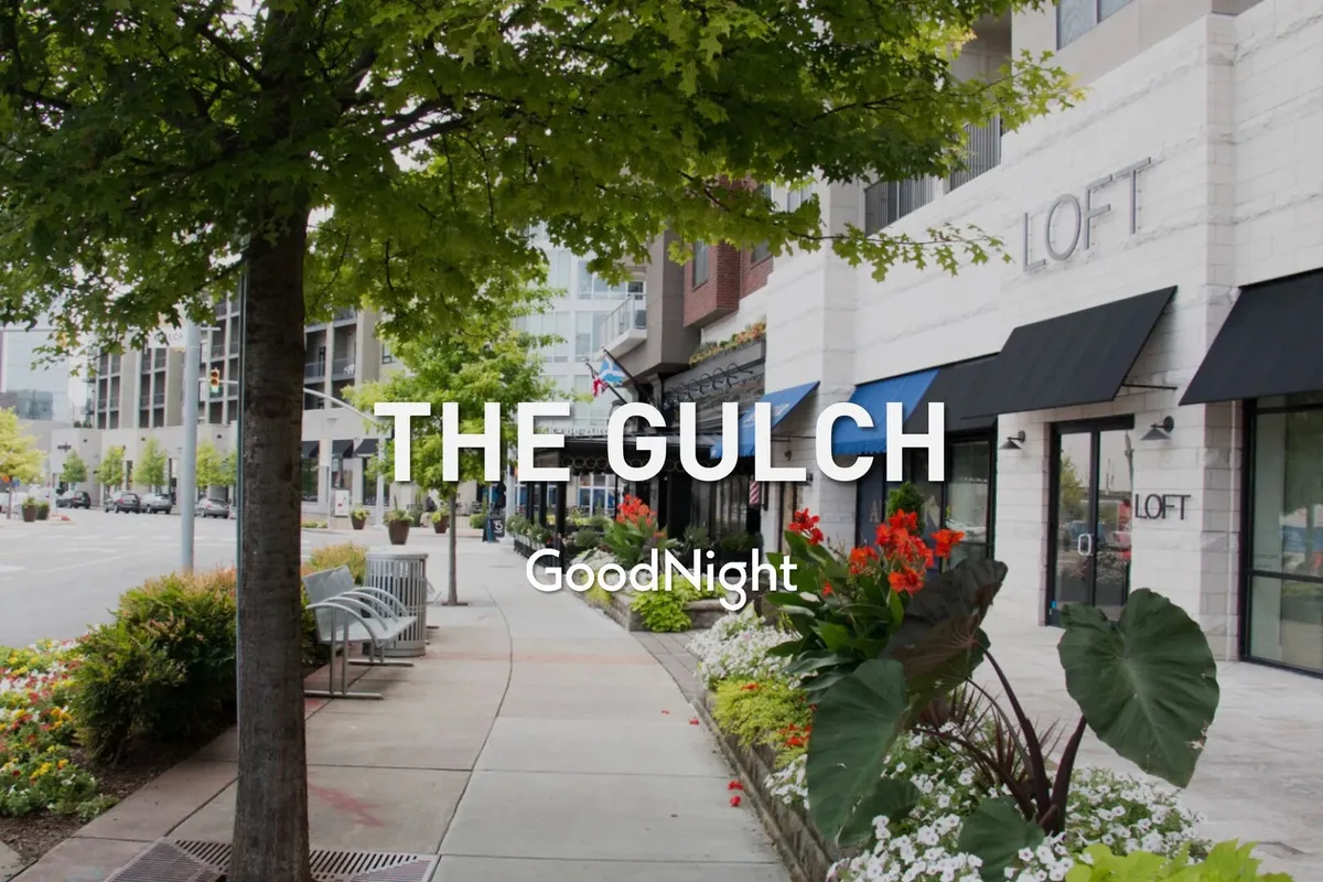 A friendly, vibrant streetscape featuring flower beds, sidewalk seating, and charming storefronts. The lively scene suggests walkability, neighborhood exploration, and opportunities for pet-friendly outings.